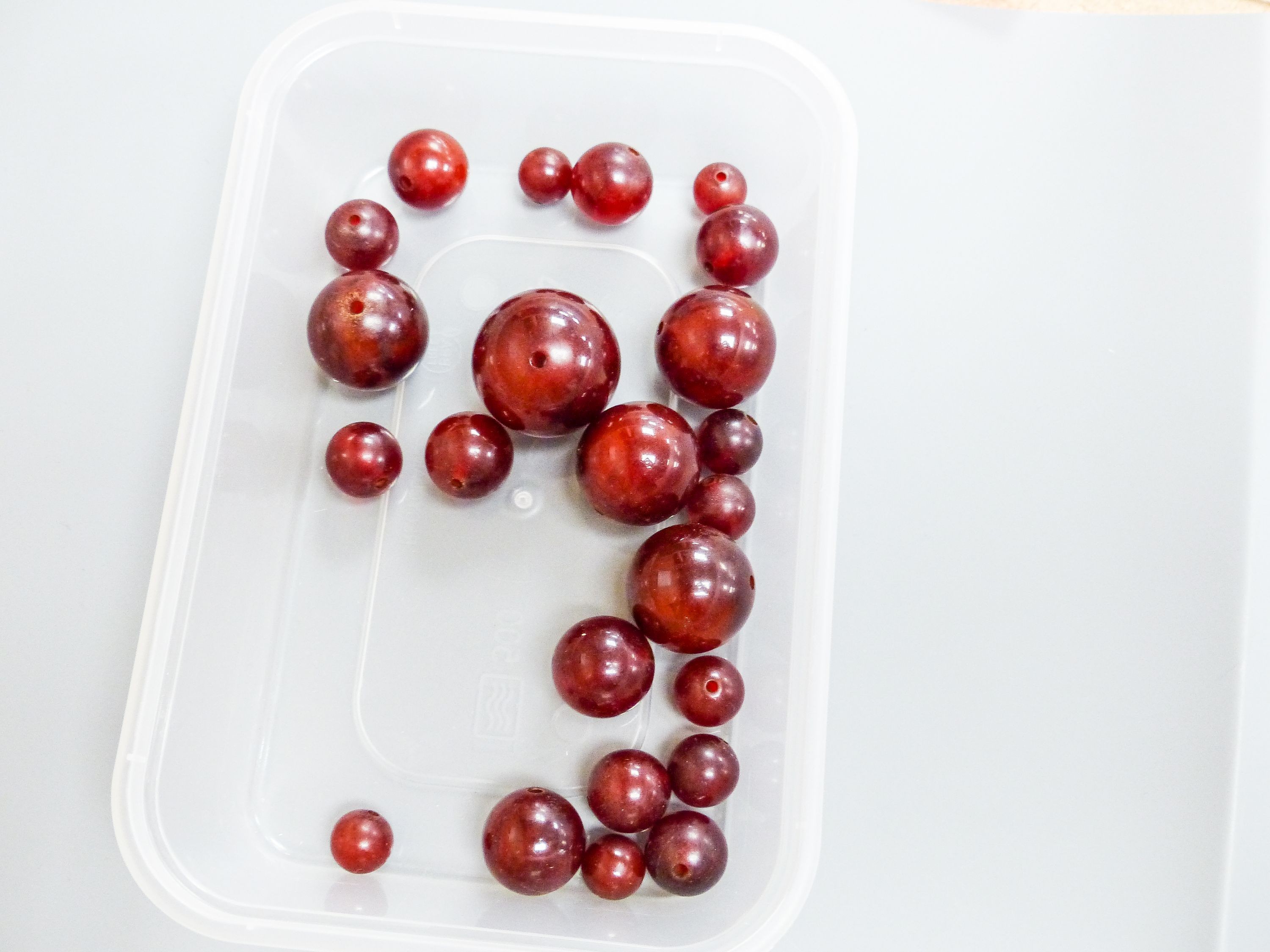 A group of loose simulated cherry amber beads and one other similar necklace, gross weight 254 grams.